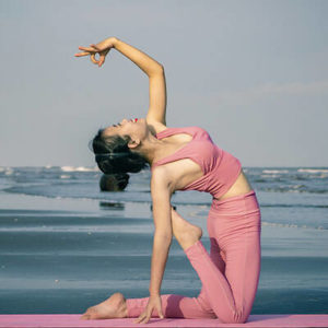 Jeune femme en position de yoga au bord de la mer